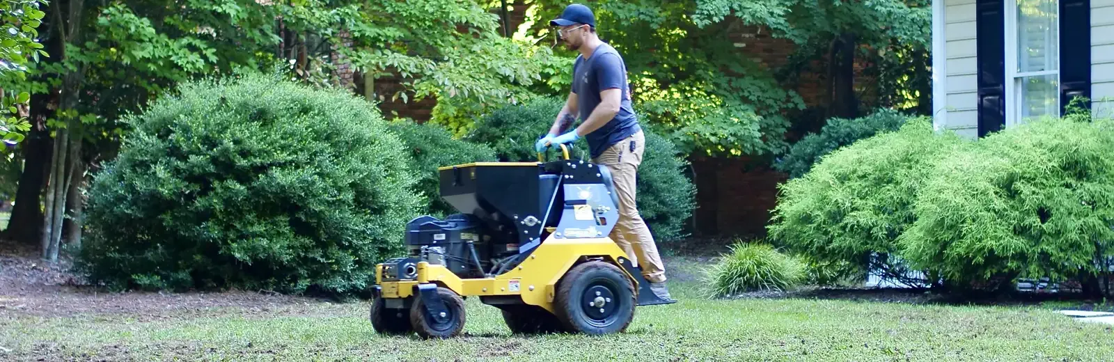 Service technician aerating lawn