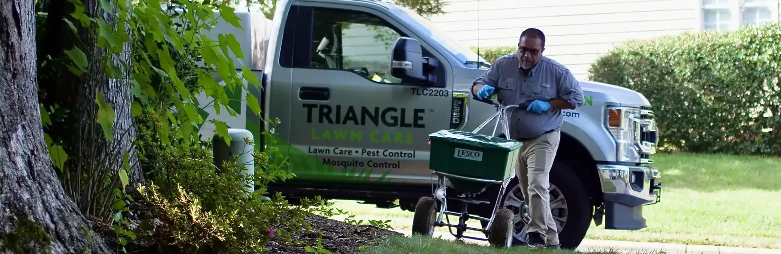 Tech spreading fertilizer on lawn